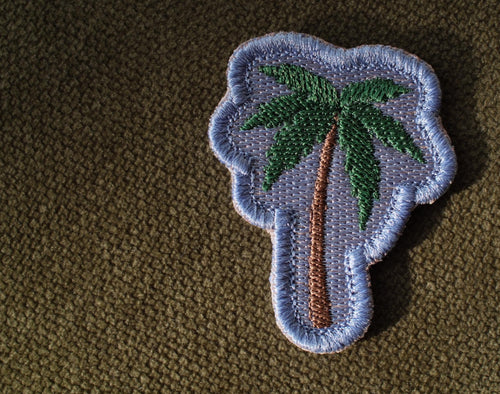 Palm tree embroidered coastal patch

Green palm tree patch with blue background

Palm tree patch embroidery and satin border detail

Coastal palm tree patch displayed on a beach bag

Palm tree patch iron-on and sew-on backing options